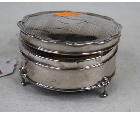 A George V silver trinket box of shaped circular form, the hinged lid with engine turned decoration and vacant cartouche havi