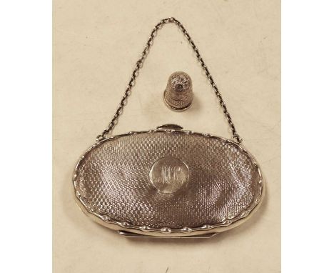 A George V silver ladies purse of oval form having engine turned decoration and monogrammed cartouche with leather partitione