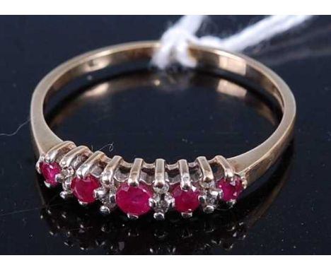 A 9ct gold, ruby and diamond set half hoop ring, arranged as five graduated round cut rubies dispersed with twin diamond poin