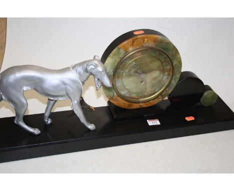 A 1930s Art Deco mantel clock, the onyx dial showing Arabic numerals, beside a grey painted spelter model of a dog, mounted o