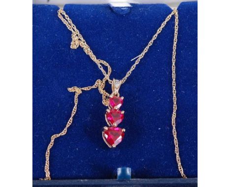 A modern 9ct gold, garnet and diamond set pendant, arranged as three graduated heart shaped garnets to a diamond set bale, al