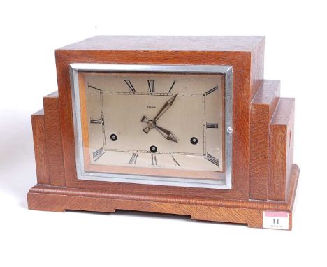 A 1930s Art Deco oak cased mantel clock, of stepped rectilinear form, the eight-day movement with Westminster chimes, the sil