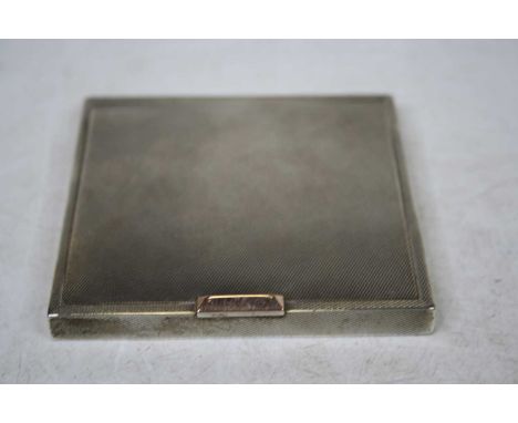 An early 20th century ladies silver powder compact of square shape having all over engine turned decoration and yellow metal 