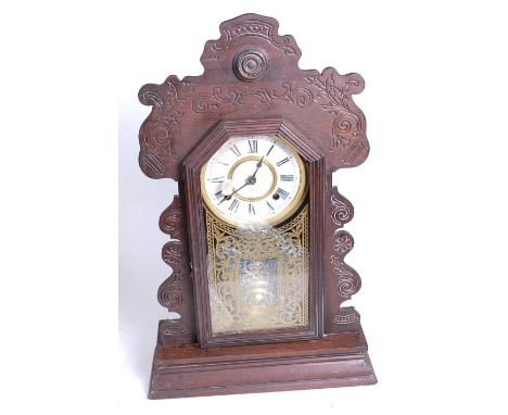 An early 20th century gingerbread type eight-day mantel clock, the chapter ring showing Roman numerals, the glazed door with 