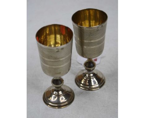A pair of early 20th century continental white metal Kiddush cups having engine turned decoration and gilt washed interiors, 