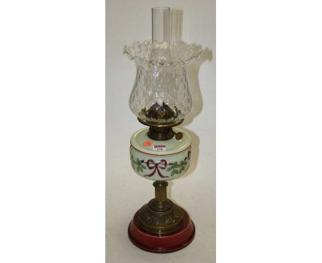 A late 19th century brass oil lamp, the clear glass shade with wavy rim above a painted green opaque glass font, on a circula