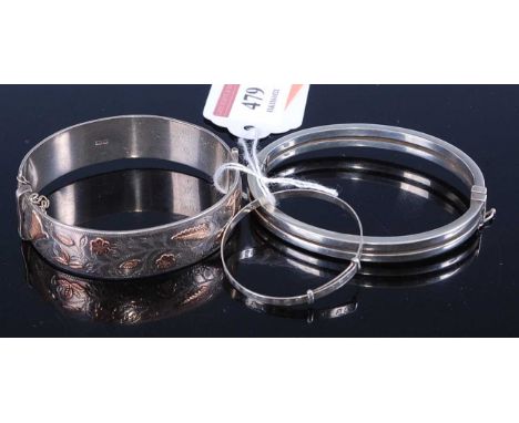 A silver hinged bangle, having raised yellow metal and engraved decoration; together with one other modern silver hinged bang
