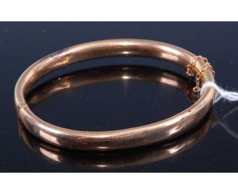 A 15ct gold hollow hinged bangle with safety chain, 11.1gCondition report: Bracelet has a couple of minute dents and some sur