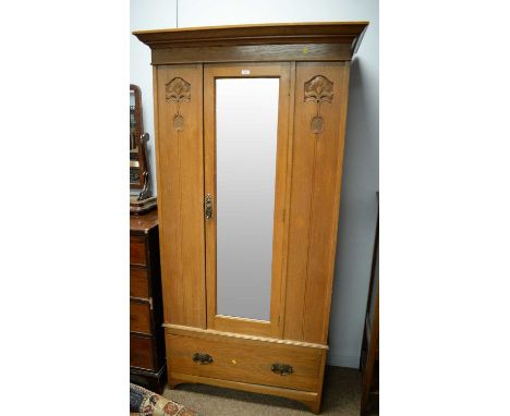 An Art Nouveau style walnut single door wardrobe, the projecting cornice above a single bevelled plate mirror door, flanked b