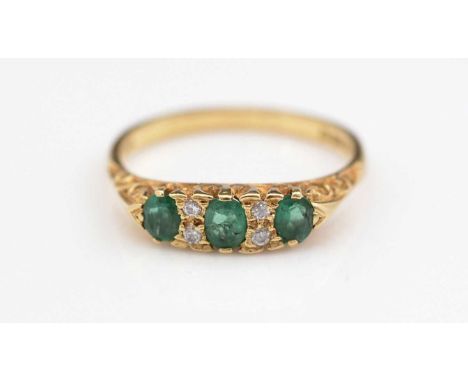 An emerald and diamond ring, the three oval facet-cut graduated emeralds parted by pairs of brilliant-cut diamonds, in a Vict