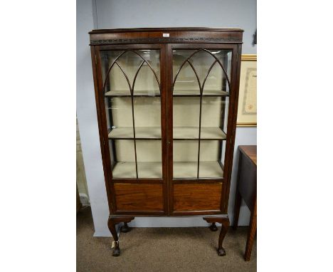 An early 20th Century mahogany display cabinet, with caddy top above a pair of astragal glazed doors, enclosing shelves, rais