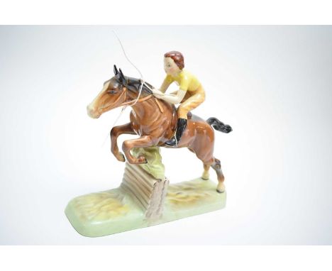 A Beswick model of a lady jockey in yellow shirt jumping a fence, 27 x 24cms high.