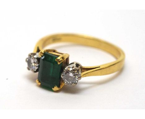 An emerald and diamond ring, the rectangular step cut emerald flanked by brilliant cut diamonds, on 18ct yellow gold shank, r