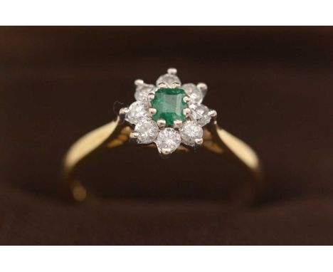 An emerald and diamond cluster ring, the central rectangular facet-cut emerald surrounded by eight brilliant-cut diamonds, to