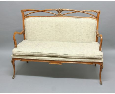 ART NOUVEAU STYLE SOFA AND ARM CHAIR, the frame, possibly beech, carved with swirling tendrils with a padded back and loose c