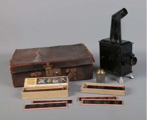 A small magic lantern projector raised on lion paw feet in leather case along with two cases of coloured lantern slides.  