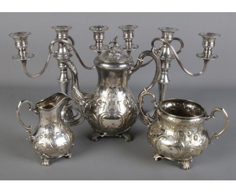 A ornate silver plate three piece teaset along with a pair of silver plate candelabra.  