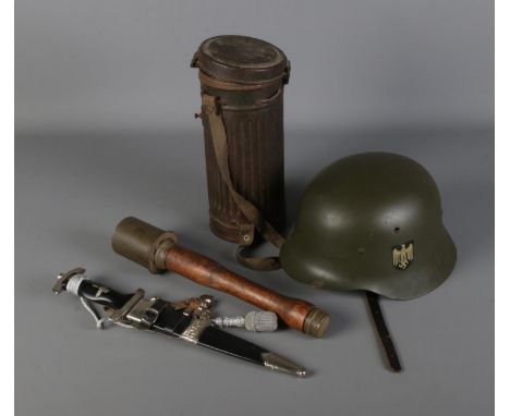A collection of replica German military items including stick grenade, helmet, dagger and metal container  