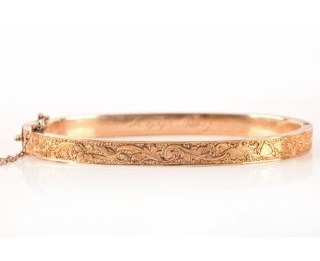A yellow metal bangle, featuring a floral engraved motif, engraved 'Betty Ayling to interior', fitted with secure clasp and s