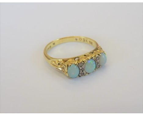 An 18ct gold, opal and diamond ring, mounted with three oval opals and with two pairs of small cicular cut diamonds, mounted 