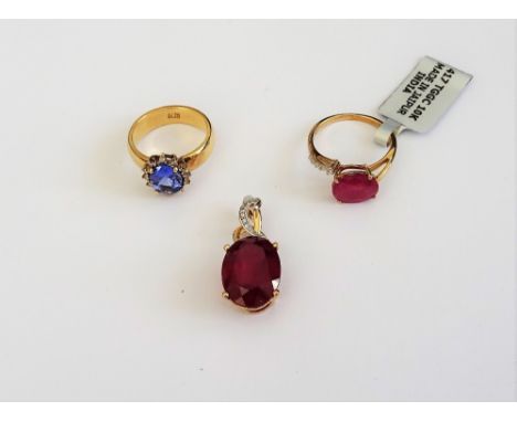 A 9ct gold ring, claw set with an oval cut treated ruby and with colourless gems to one side, a gold, tanzanite and diamond o