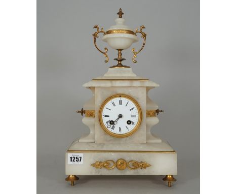 An alabaster mantel clock, late 19th century, with gilt metal mounts and urn surmount over a white enamel dial and plinth bas