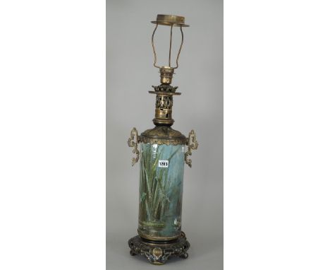 A pottery table lamp painted with dragonfly and water lily around a pond, enclosed in a pierced Chinese style gilt metal moun