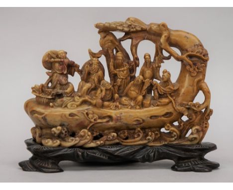 A Chinese soapstone carving, late 19th/20th century, carved with the eight Immortals on a tree trunk raft, 18.5cm. wide, wood