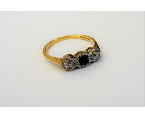 An 18ct gold, sapphire and diamond set three stone ring, mounted with a cushion shaped sapphire to the centre, between two cu