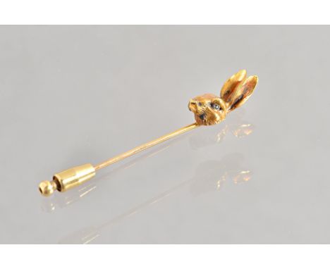 A gold stick pin, the finial modelled as a hare's head, with green gem set eyes, gross weight 7.8 gms. Illustrated.