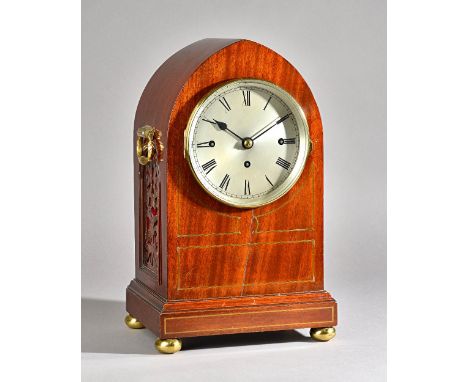 An Edwardian mahogany and brass inlaid bracket clock of lancet form, with silvered dial and twin brass handles over pierced f