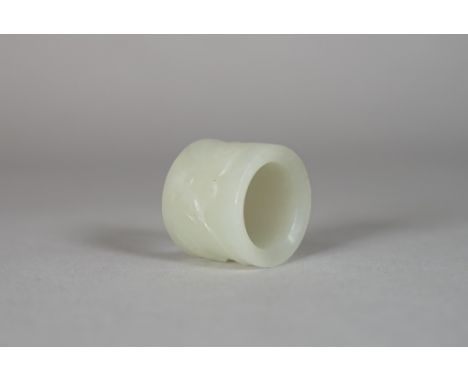 A Chinese pale celadon jade archer's ring, Qing Dynasty, carved with lotus flowers and cash, 2.5cm. high. 