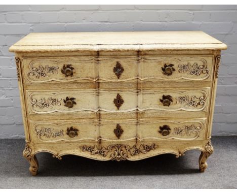 An 18th century style stripped oak commode, the shaped top over three long drawers, on shell capped scroll feet, 120cm wide x