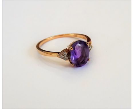 A gold, amethyst and diamond ring, claw set with the oval cut amethyst to the centre, between circular cut diamond set three 