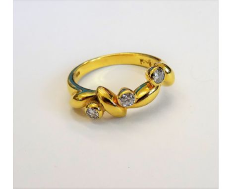 A gold and diamond ring, collet set with three circular cut diamonds, in an abstract design, detailed 750, ring size N, gross