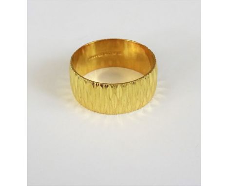 An 18ct gold wide band wedding ring, with a cut and textured finish, London 1971, weight 8.8 gms, ring size W.