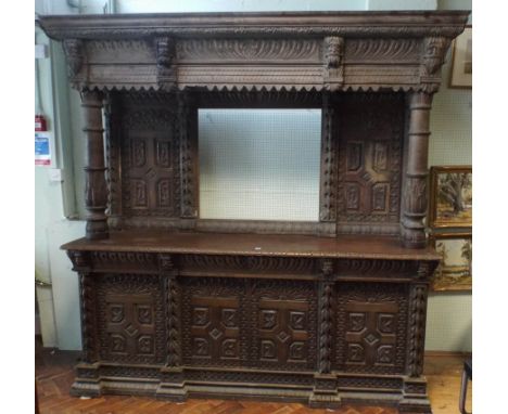 An imposing heavily carved 19th century oak sideboard, of architectural form, with large overhanging cornice above back panel