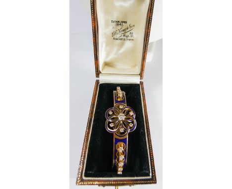 A late Victorian 18ct yellow gold diamond and blue enamel ladies hinged bangle set with a central brilliant cut diamond flowe