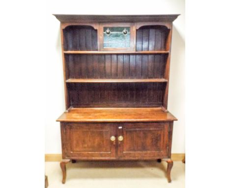 A 1920's oak dresser with shelf back and leaded glazed cabinet standing on a two door cupboard style base with cabriole feet,