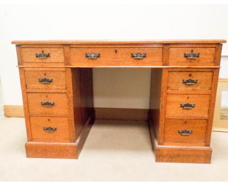 A 4' Edwardian oak pedestal desk, fitted nine drawers   The top has a piece of hardboard fitted 