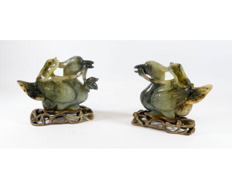 A pair of Chinese russet jade carved mythical birds on hardwood stands, 13cms tall 15cms across      One has the iris missing