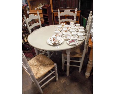 A circular grey painted dining table and a set of four ladder back chairs with rush seats 