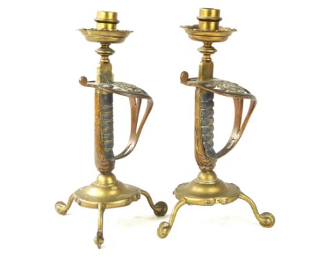 A pair of military themed sword grip candlesticks, late 19th CenturySword guards with Queen Victoria's cyper surmounted by a 