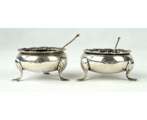 A pair of silver saltsOf circular form, with an applied fluted rim, raised on three shell capped hoof feet, with matched spoo