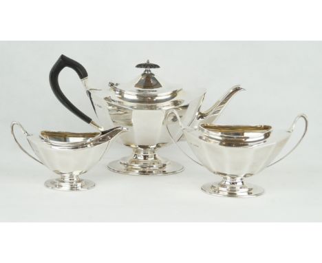 A silver three piece tea serviceOf oval panelled form, raised on oval pedestal feet, comprising, teapot, sugar bowl, milk jug