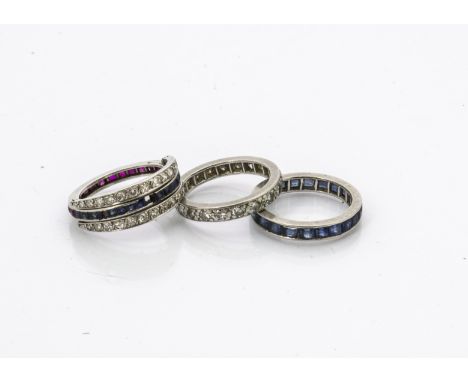 Three diamond, sapphire and ruby set eternity rings, comprising a full diamond example, ring size N, a full sapphire example,