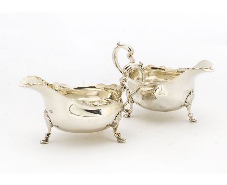 A pair of Edwardian silver sauce boats by Thomas Bradbury &amp; Sons, pie crust rims on three hoof supports, London 1906, 20.