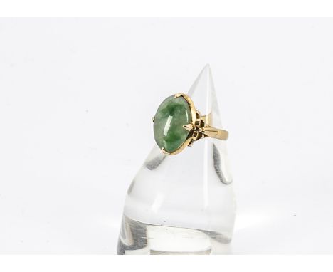 A continental jade signet ring, the oval cabochon jade central stone in four claw setting, ribbon decorated shoulders on a pl