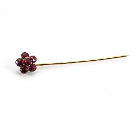 A 19th Century ruby foil backed stick pin, the mixed cut circular rubies in rubbed over settings on a yellow metal pin, 6.5cm