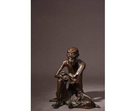 C17th Chinese bronze figure of an immortal, cast in seated position with his right hand resting on his knee, 21.5cm high.   P